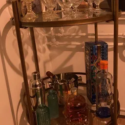 Glazen vitrinekast met flesjes sterkedrank en vintage baruitrusting zoals shakers en jiggers
