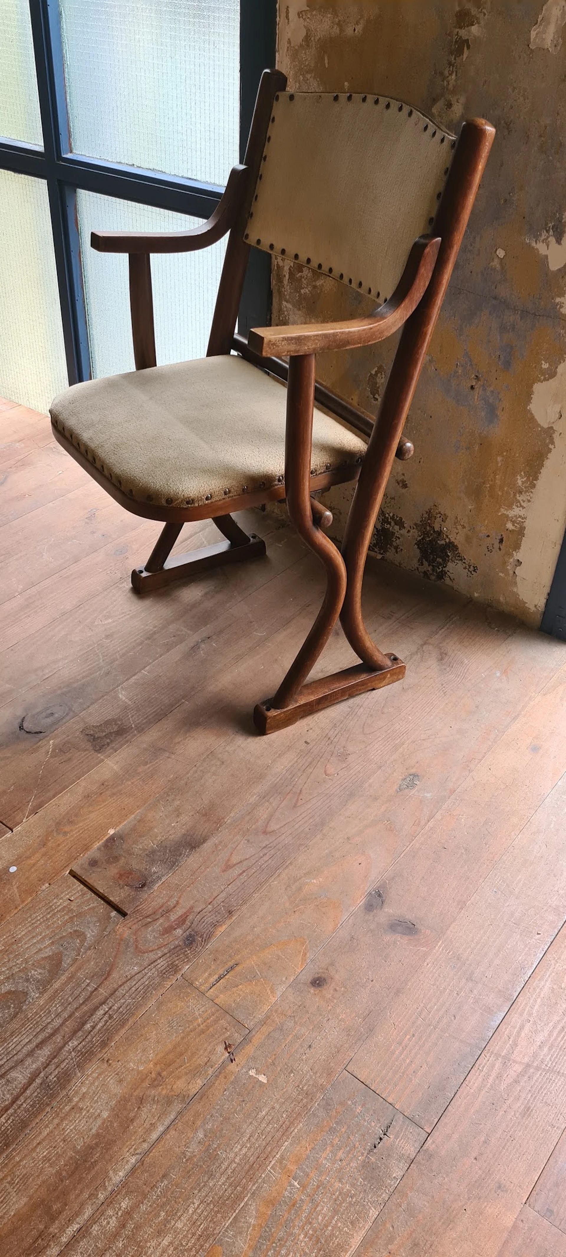 Houten stoel met beige zitting en gebogen armleuningen op houten vloer