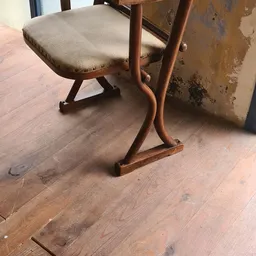 Houten stoel met beige zitting en gebogen armleuningen op houten vloer
