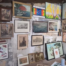 Witte muur volgehangen met diverse ingelijste prenten, schilderijen en kunstwerken in verschillende stijlen en formaten