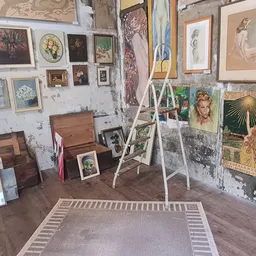 Winkelvloer met kunstwerken aan muren, ladders, houten meubels en kunstzinnige objecten uitgestal