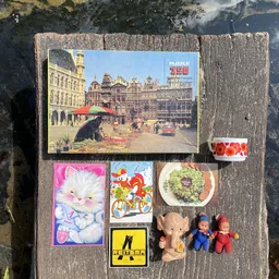 Verzameling tweedehands items: puzzel, speelgoed, servies, tape en knuffels op houten ondergrond