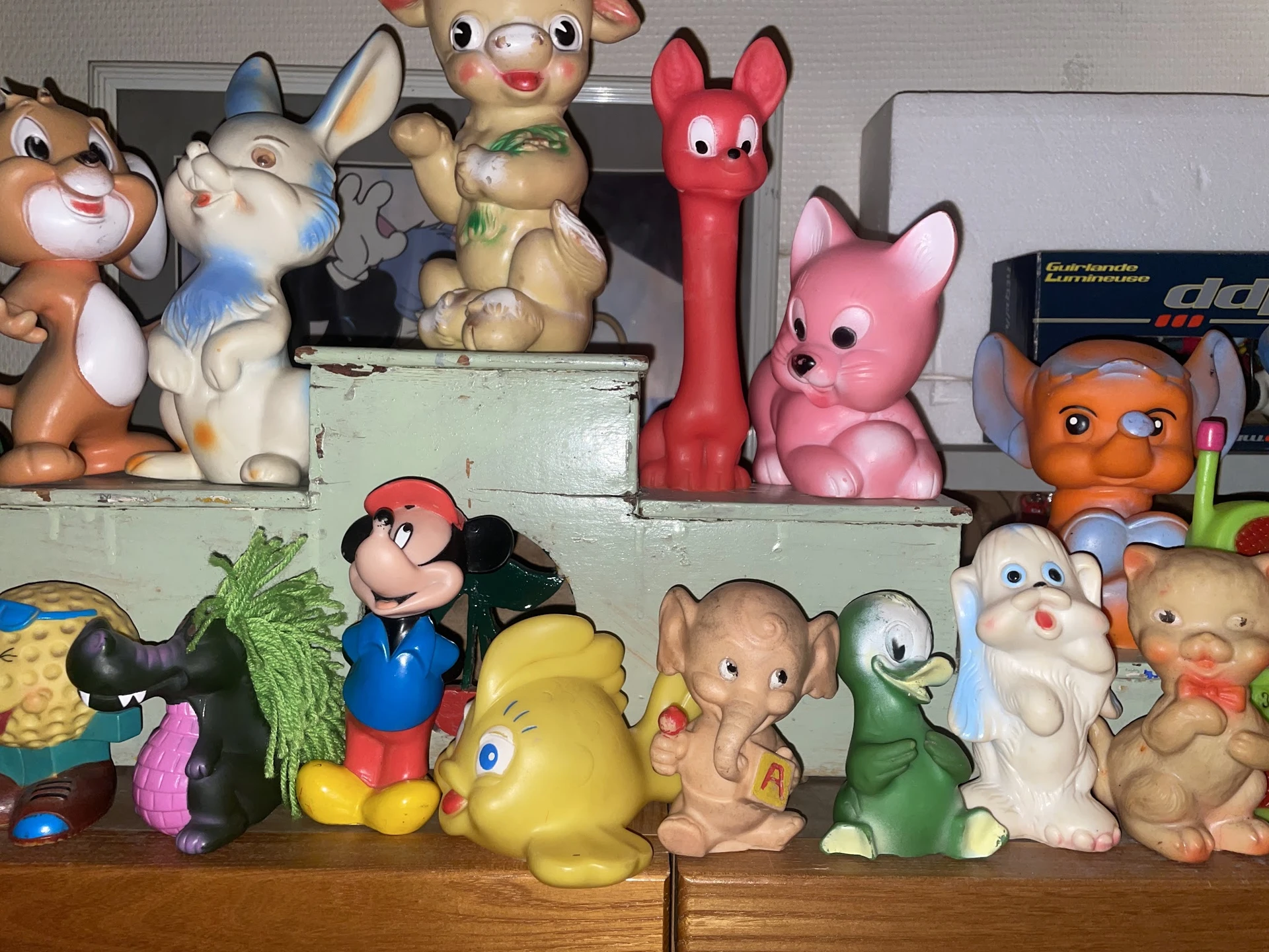 Verzameling vintage speelgoed en knuffels op houten meubel: Disney-figuren, dieren en poppen