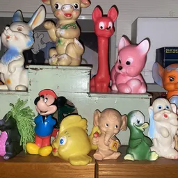 Verzameling vintage speelgoed en knuffels op houten meubel: Disney-figuren, dieren en poppen