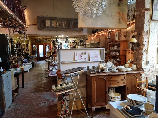 Ruim interieur van kringloopwinkel met diverse meubels, servies, decoratie en huisraad uitgestald