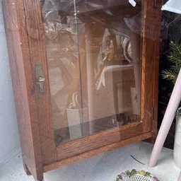 Houten vitrinekast met glazen deuren en decoratieve items binnenin