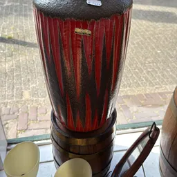 Rode vaas of decoratief object met zwarte streeppatroon, gezien vanaf boven tegen een raam
