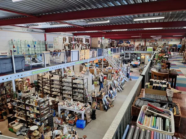 Overzicht van de winkelvloer met stellingen vol tweedehands spullen, boeken en huishoudartikelen