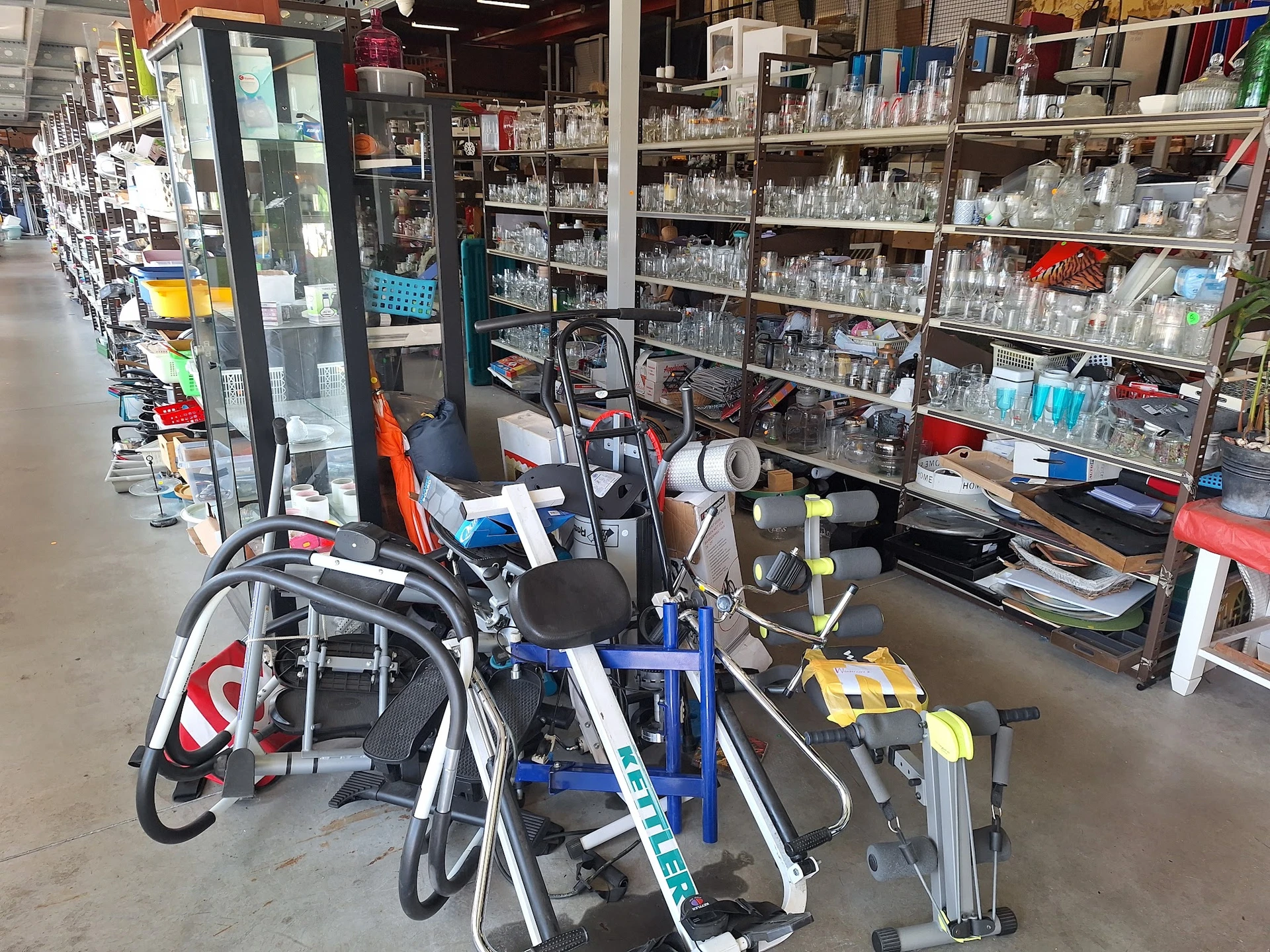 Verschillende tweedehandsartikelen op een tafel: fietsen, fietsaccessoires en huishoudelijke spullen