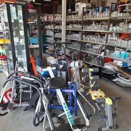 Verschillende tweedehandsartikelen op een tafel: fietsen, fietsaccessoires en huishoudelijke spullen