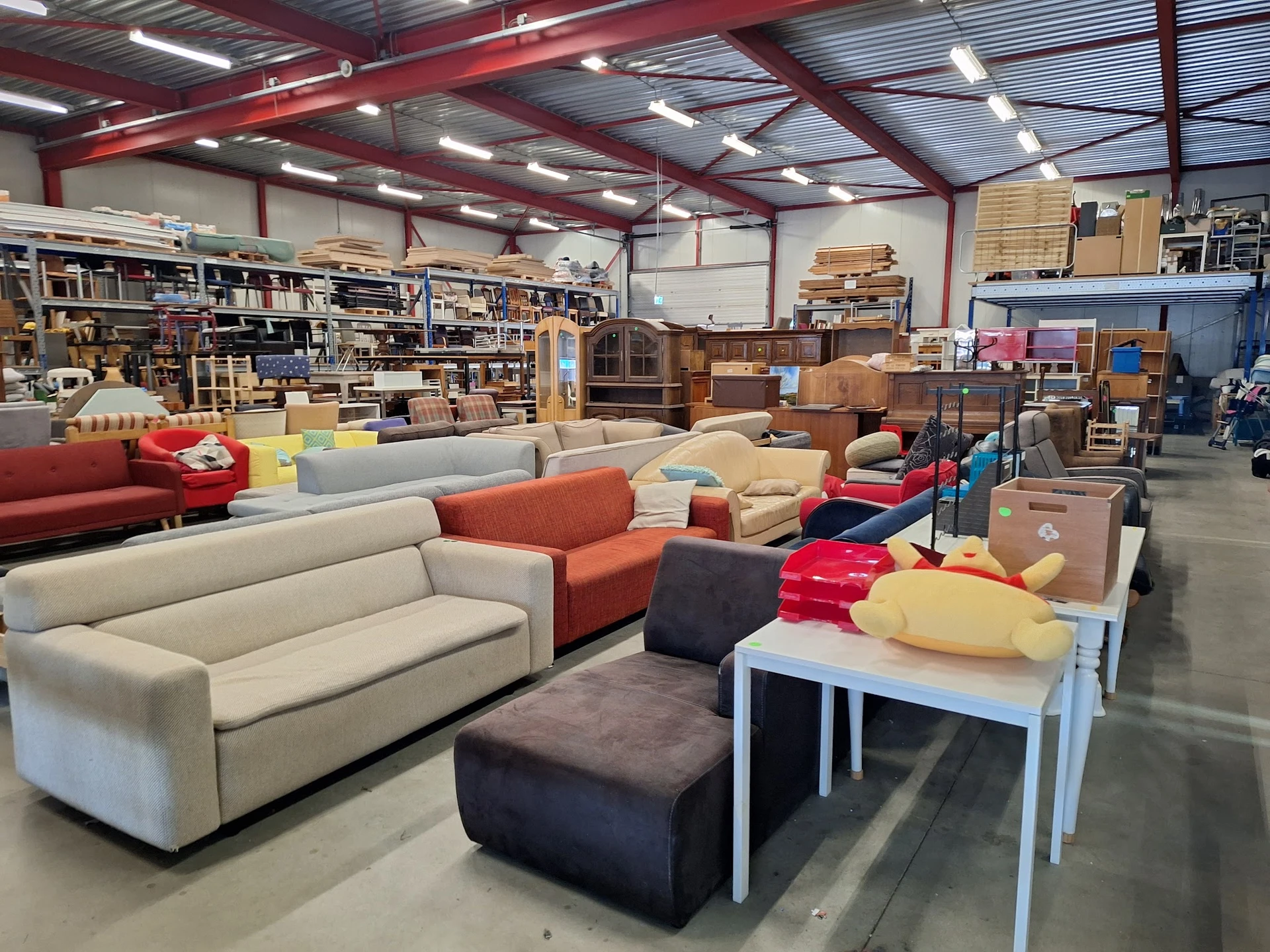 Winkelvloer met diverse meubels: banken, stoelen, tafels en ander huisraad; stellingen en opslag op de achtergrond