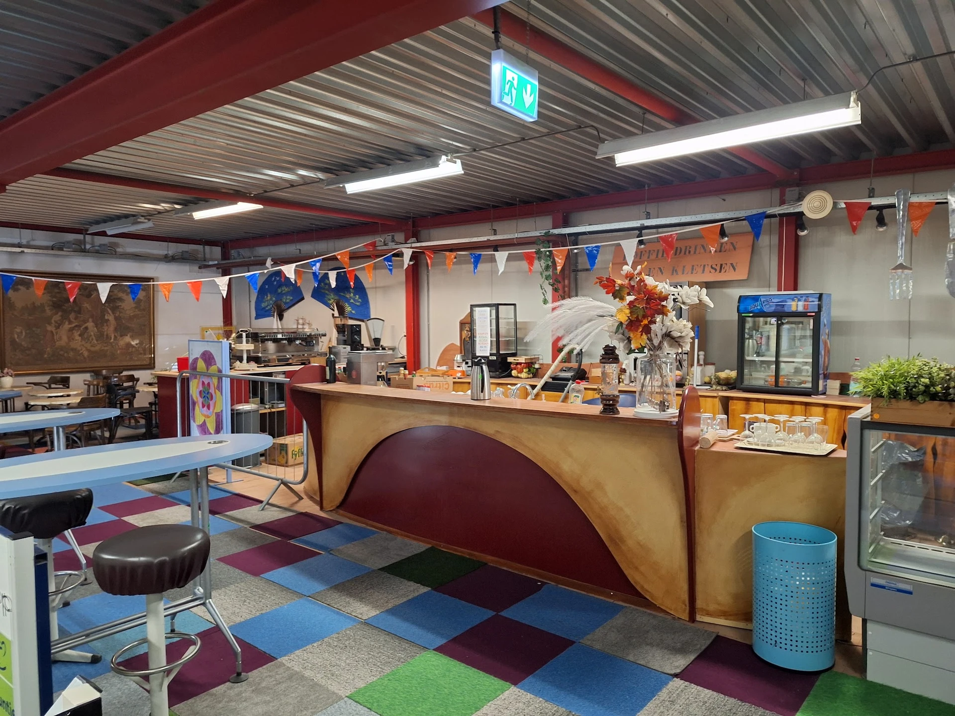 Winkelvloer met gekleurde tegels, toonbank, stellingen en decoraties in een kringloopwinkel
