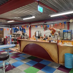 Winkelvloer met gekleurde tegels, toonbank, stellingen en decoraties in een kringloopwinkel