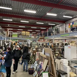 Overzicht van de winkelvloer met stellingen, rekken en uitgestalde spullen in een grote hal met rode balken