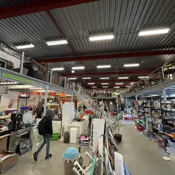 Winkelvloer van kringloopwinkel met stellingen, artikelen en bezoekers in overzicht