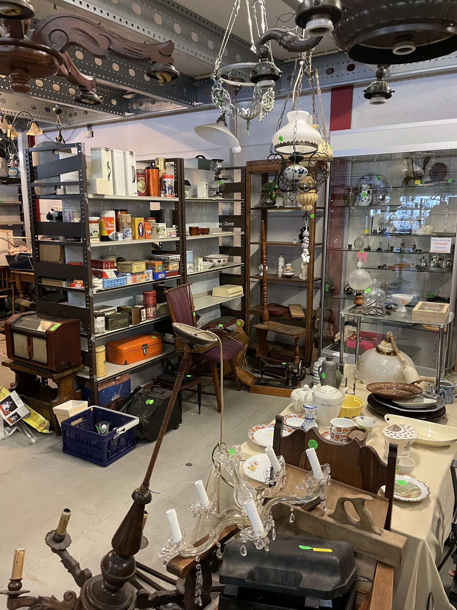 Winkelvloer met stellingen, vitrines, serviesgoed, lampen en diversen huisraad in een kringloopwinkel