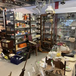 Winkelvloer met stellingen, vitrines, serviesgoed, lampen en diversen huisraad in een kringloopwinkel
