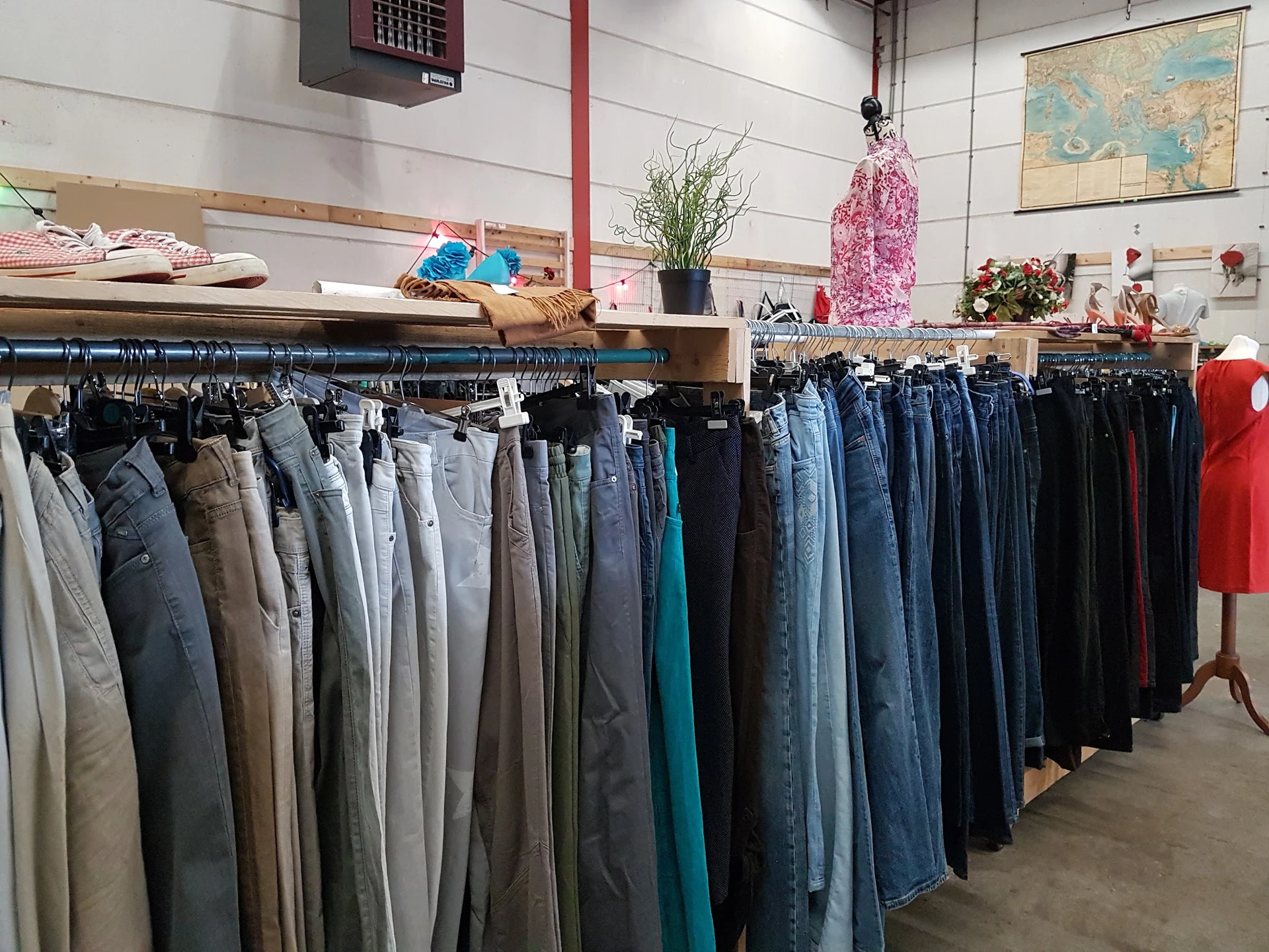 Rekken met tweedehands jeans en broeken in verschillende kleuren en maten