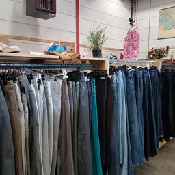 Rekken met tweedehands jeans en broeken in verschillende kleuren en maten