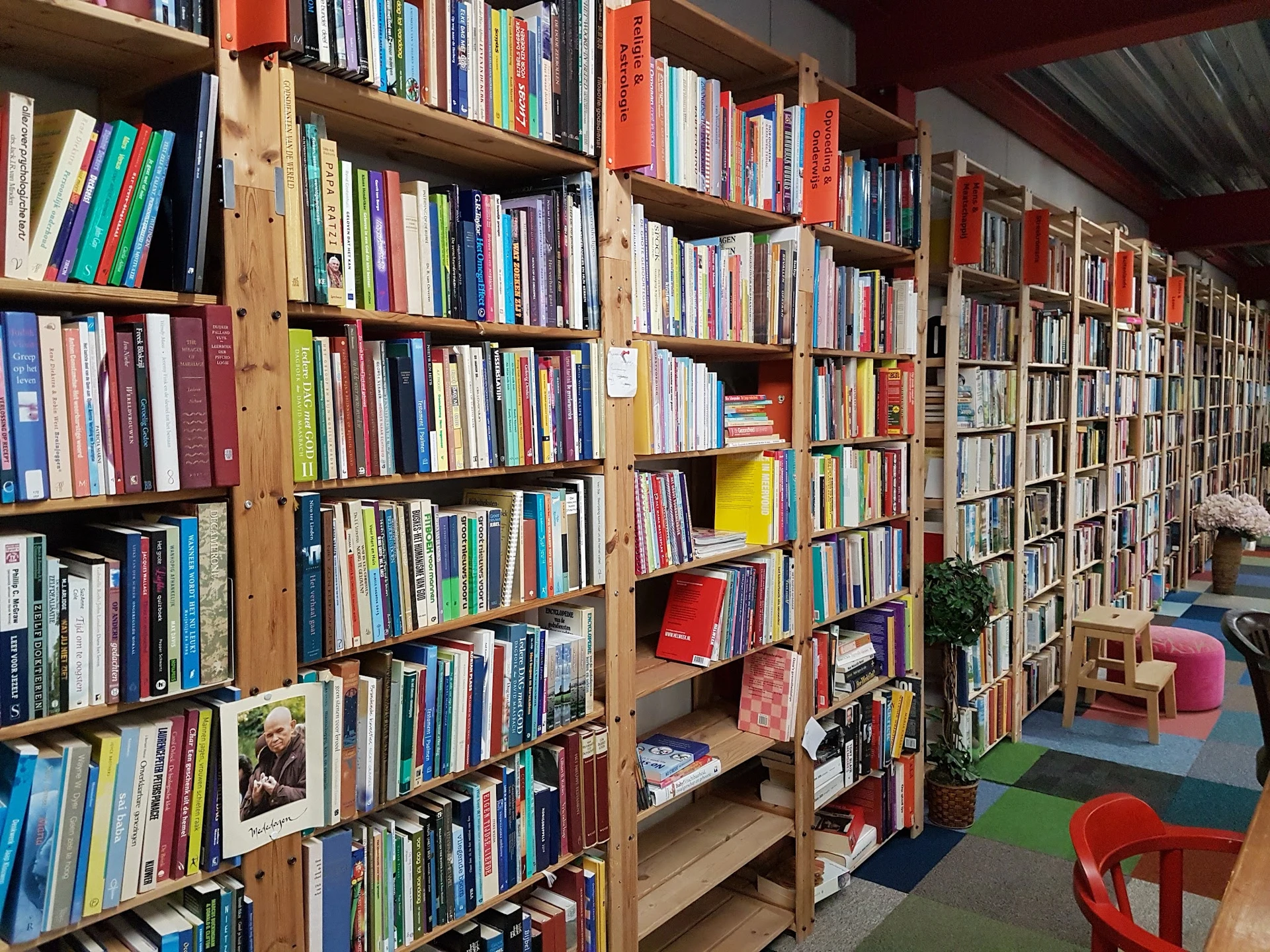 Boekenkasten vol tweedehands boeken in verschillende kleuren, met kleurrijke zithoeken op de winkelvloer