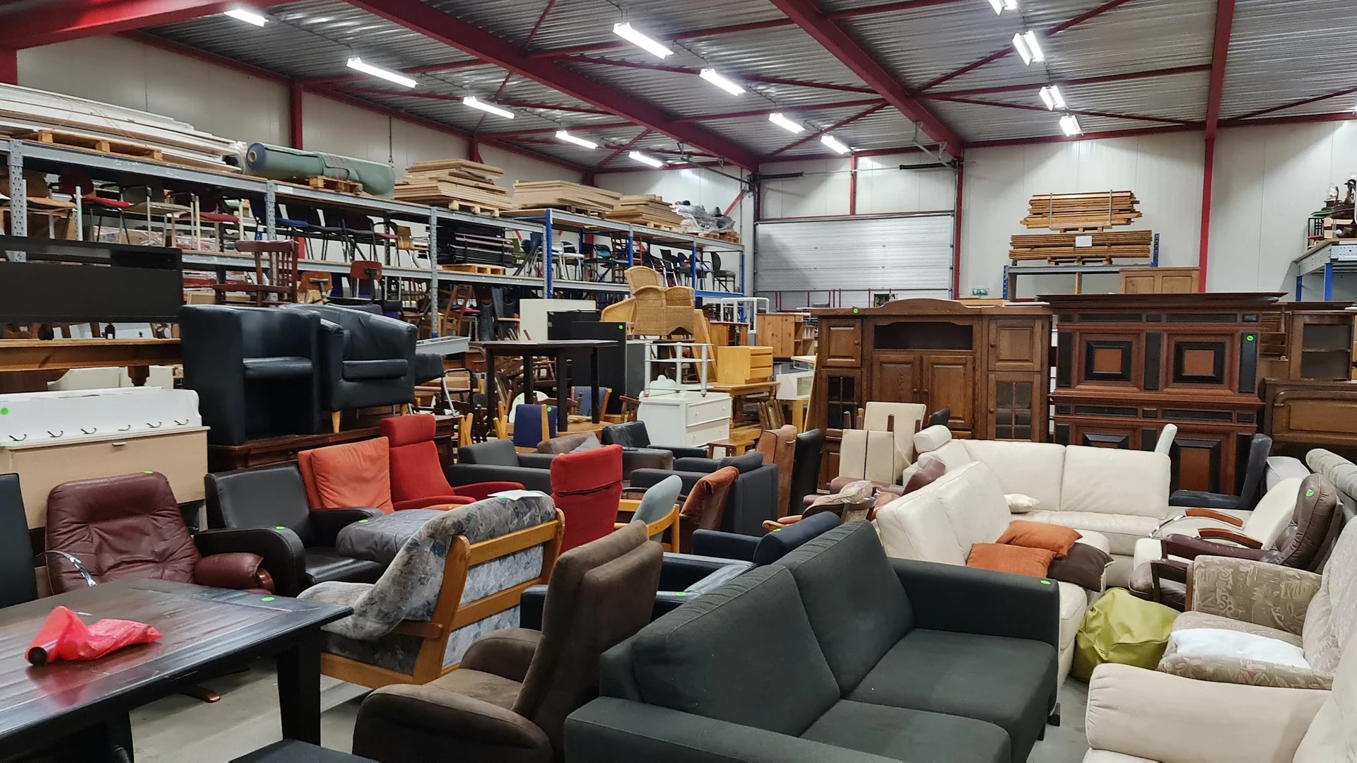 Diverse meubels in een kringloopwinkel: banken, stoelen en kasten in verschillende stijlen en kleuren