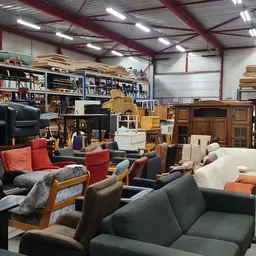 Diverse meubels in een kringloopwinkel: banken, stoelen en kasten in verschillende stijlen en kleuren