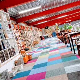 Ruim winkelinterieur met boekenkasten, gekleurde patchwork vloer en rode balkenplafond