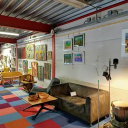 Ruim interieur van kringloopwinkel met kleurrijke vloer, kunstwerken aan wanden, meubels en huisraad
