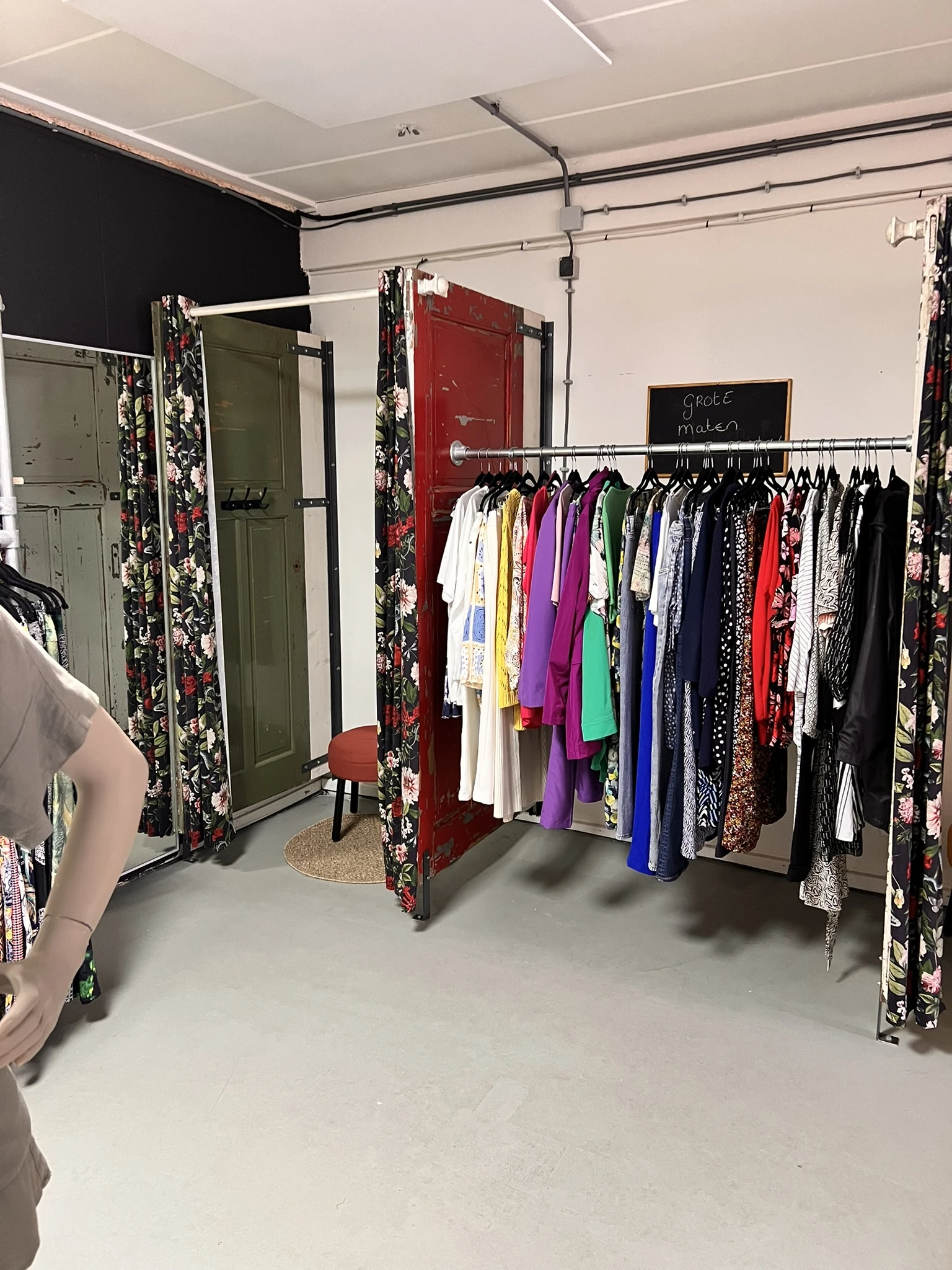 Rekken met tweedehands kleding in diverse kleuren, waaronder jurken en jassen op hangers
