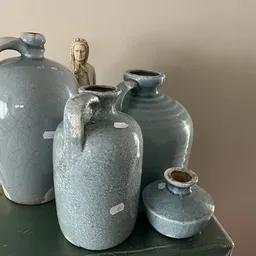 Vier grijsblauwe steengoed kruiken en kannen, waarvan één met decoratief vrouwenfiguur erop