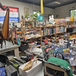 Rommelig interieur van kringloopwinkel met boekenkasten, speelgoed, elektronica en diverse spullen