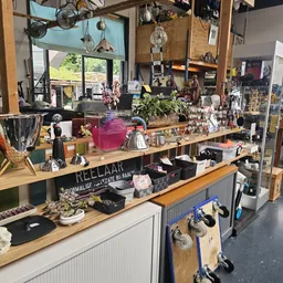 Winkelcounter met houten blad, diverse huishoudelijke artikelen, decoraties en plantjes op een houten toonbank met vakken ero