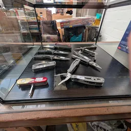 Verzameling van verschillende vouwmessen en zakmes uitgestald op een zwarte tafel in de winkel
