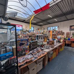 Winkelvloer met tafels vol uitgestalde spullen, stellingen en kasten langs de wanden in een kringloopwinkel