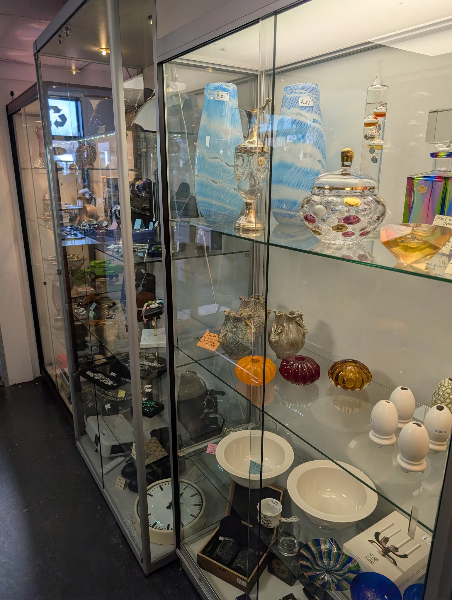 Vitrinekasten met uitgestalde glazen flessen, parfumflessen, decoratieve bollen en serviesgoed