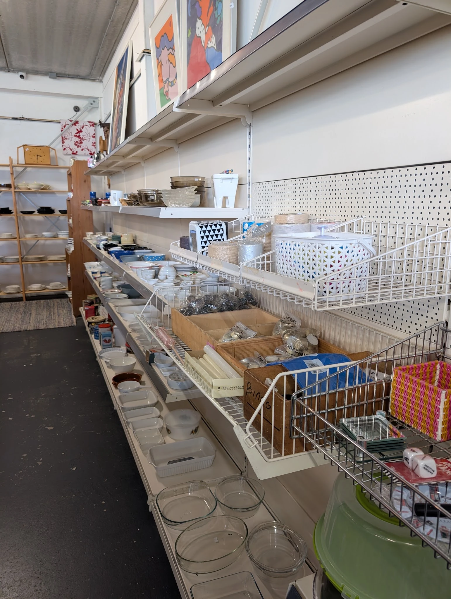 Toonbanken met diverse huishoudelijke artikelen, dozen en bakken met spullen in kringloopwinkel