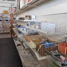 Toonbanken met diverse huishoudelijke artikelen, dozen en bakken met spullen in kringloopwinkel