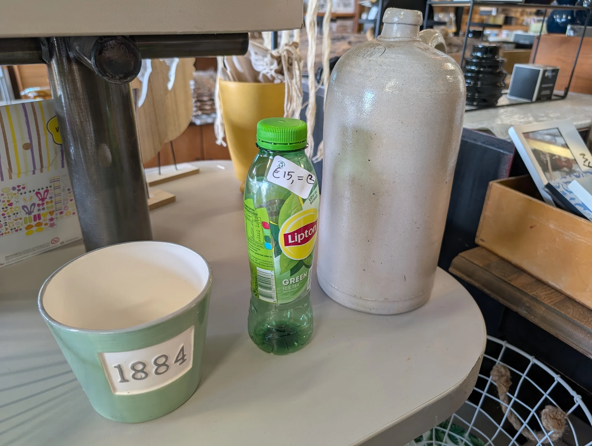 Tafel met koffiekopje, flesje Lipton thee en thermoskan in een kantooromgeving