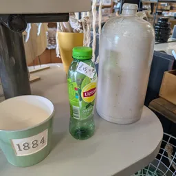 Tafel met koffiekopje, flesje Lipton thee en thermoskan in een kantooromgeving