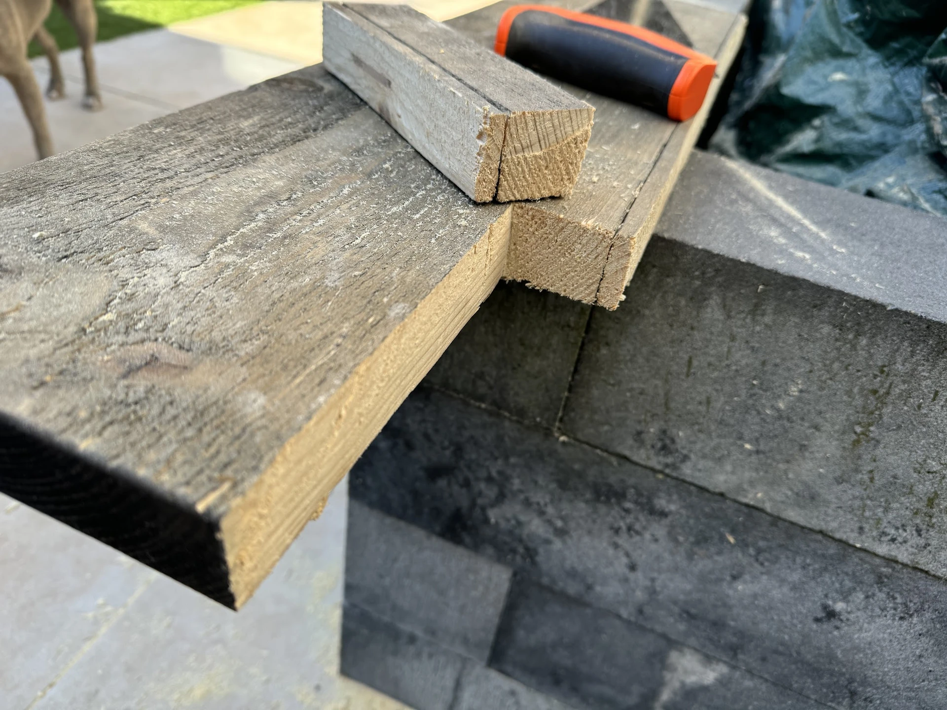 Close-up van een houten werkstuk op een steenachtergrond met gereedschap op de achtergrond