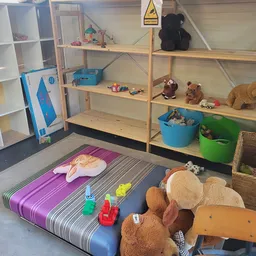 Kinderspeelhoek met speelmat, speelgoed, knuffels en opbergboxen in een kringloopwinkel