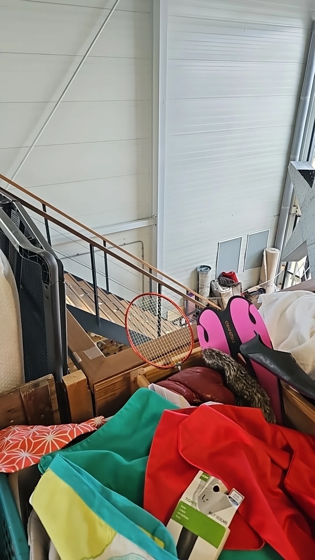 Diverse gebruikte spullen op een trap: tennisracket, roze sportschoenen, kleding en ander huishoudelijk goed