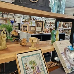 Houten toonbank met decoratieve objecten, foto's en huishoudartikelen in een kringloopwinkel