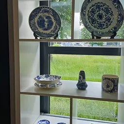 Blauw-wit porselein servies en decoratieve objecten op een vensterbank.
