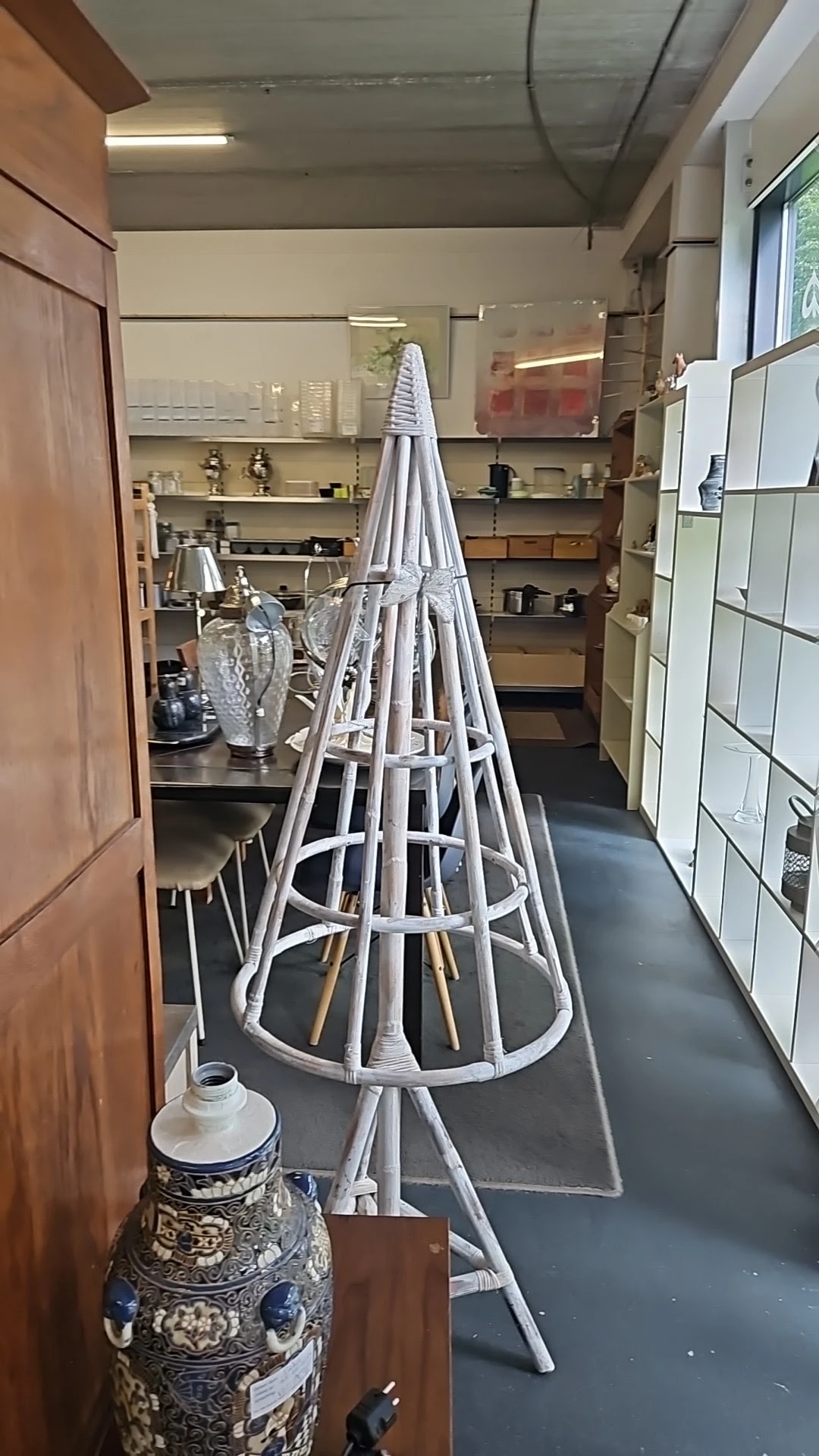 Witte metalen paralustandaard in conische vorm in een kringloopwinkel