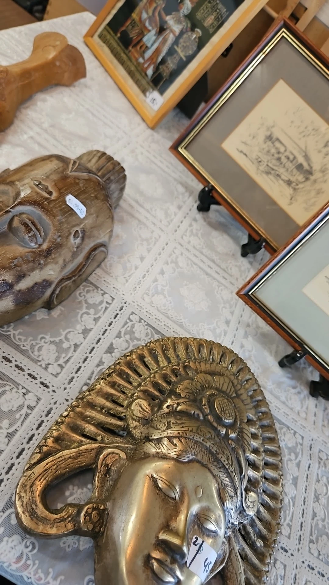 Goudkleurig decoratief schaalstuk met reliëfwerk, gedeeltelijk zichtbaar op een witte tafelkleed