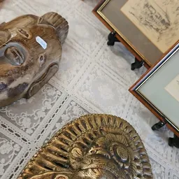 Goudkleurig decoratief schaalstuk met reliëfwerk, gedeeltelijk zichtbaar op een witte tafelkleed