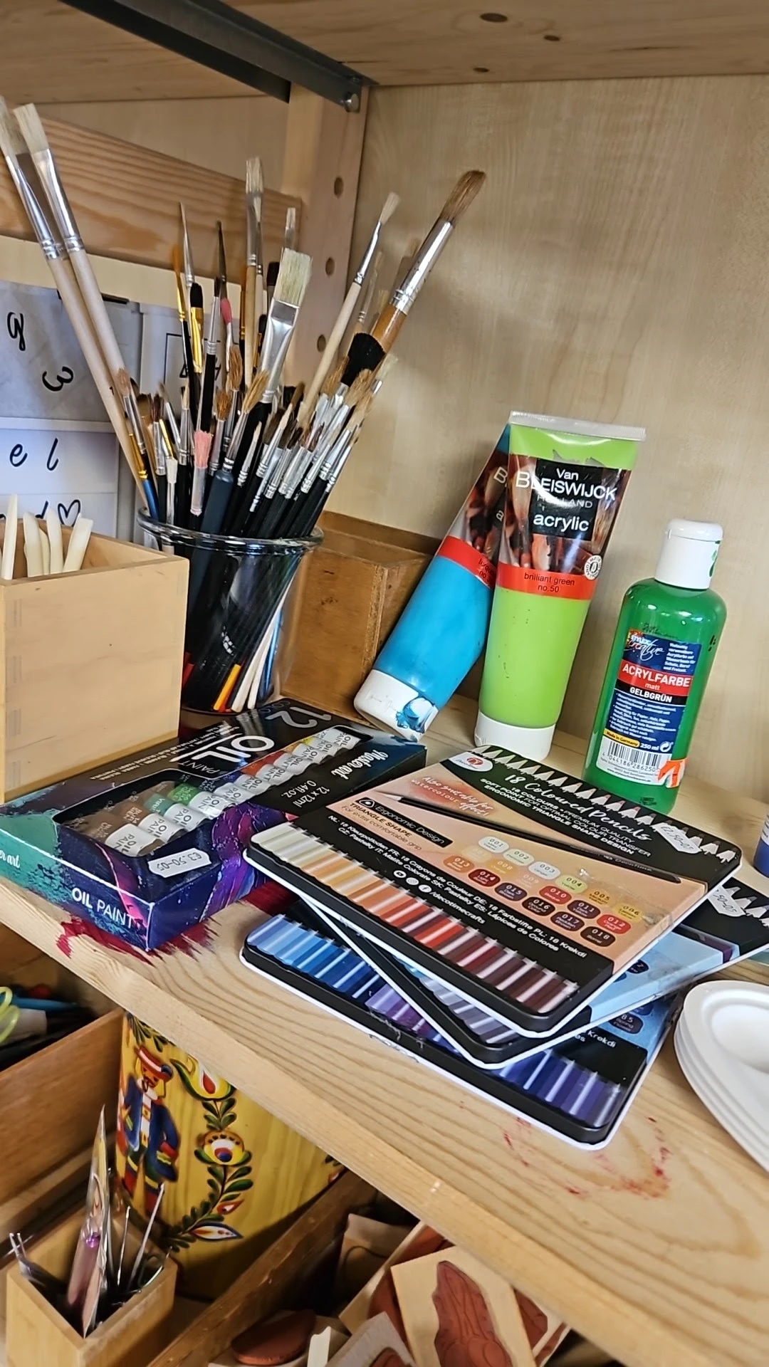Verzameling kunstbenodigdheden: verfkwasten, acrylverf, olieverf, verfpaletten en tekensetjes op een tafel
