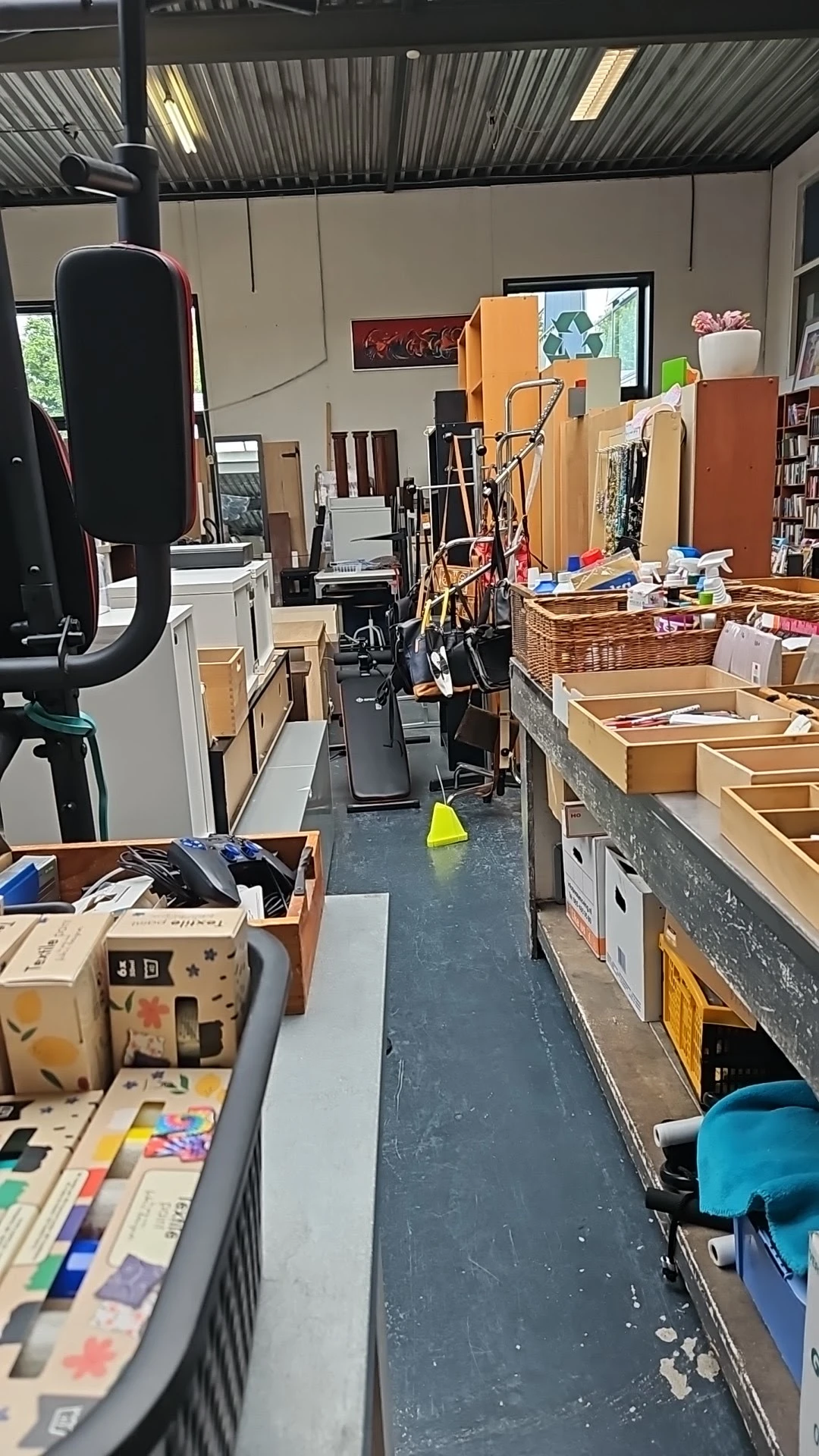 Winkelinterieur met dozen, manden en diverse spullen langs de wanden en op de grond