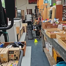 Winkelinterieur met dozen, manden en diverse spullen langs de wanden en op de grond
